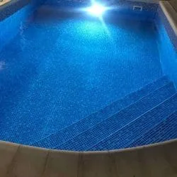 Pool mit Mosaikstufen und eingeschalteter Unterwasserbeleuchtung