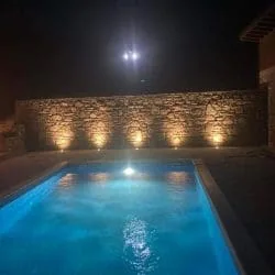 Pool am Abend neben einer Stützmauer aus Stein mit Gartenlampen