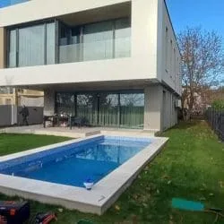 Rechteckiger Pool auf einer grünen Wiese vor einem zweistöckigen Haus