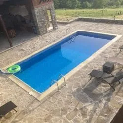 Rechteckiger Pool mit Steinbelag, Leiter und Grillpavillon